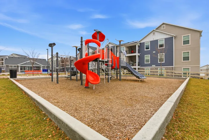 Recreational playground featuring multi-level structures, red spiral slides, gray straight slide, and a wood chip surface