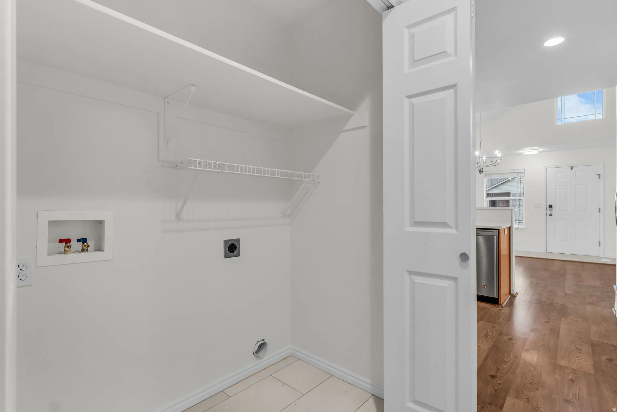 Dedicated laundry area featuring white walls, a single wire shelf, and a utility shelf