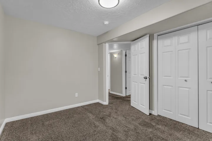 Neutral-toned room with plush carpet flooring, white baseboards, and a flush-mount ceiling light