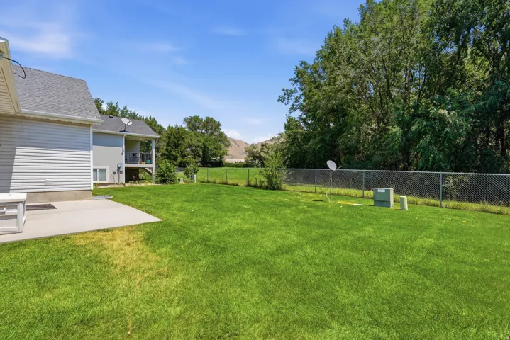 Expansive lawn with a chain-link fence bordering mature trees and distant hills
