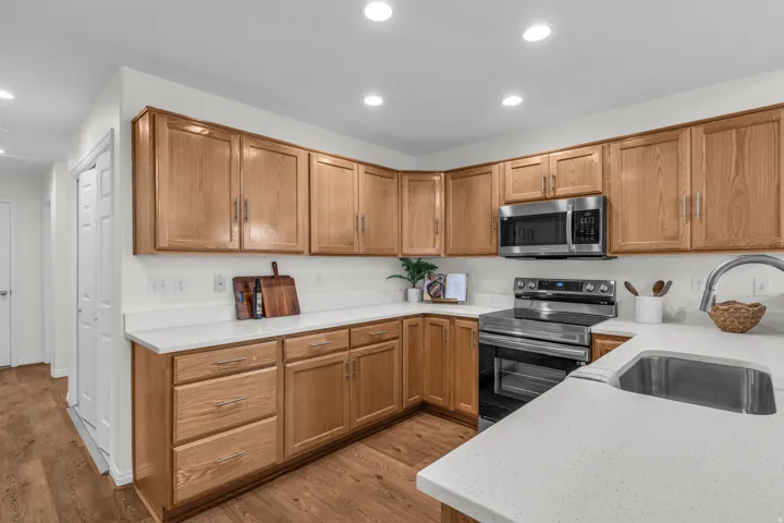Kitchen featuring light wood cabinetry, light countertops, stainless steel appliances, and wood-finish flooring