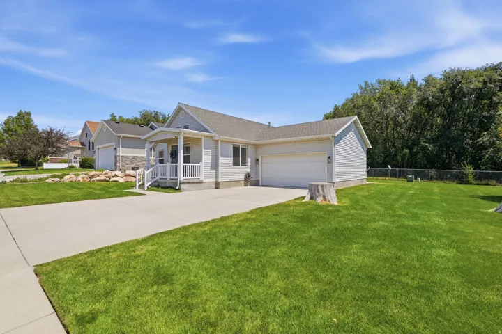 Ranch-style residence featuring light-colored siding, an attached two-car garage, and a covered porch with white railings