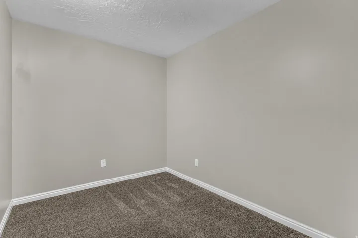 Neutral-toned walls complement the textured carpet flooring and white baseboards