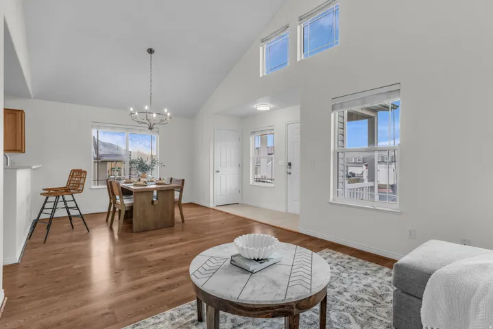 Open-concept living space featuring wood-finish flooring, vaulted ceilings, and white walls