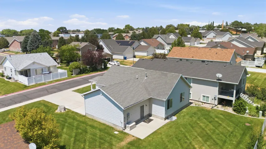 Rear exterior featuring light grey siding, a covered patio, and a well-maintained lawn