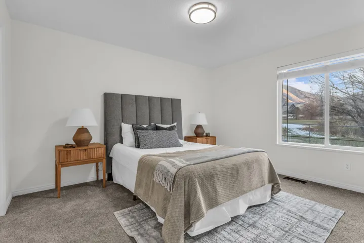 Spacious room featuring a large window with mountain scenery, plush carpet flooring, a ceiling-mounted light fixture, and white painted walls