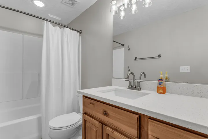 Bathroom featuring a light-toned vanity with an integrated sink, a speckled countertop, and a brushed nickel faucet