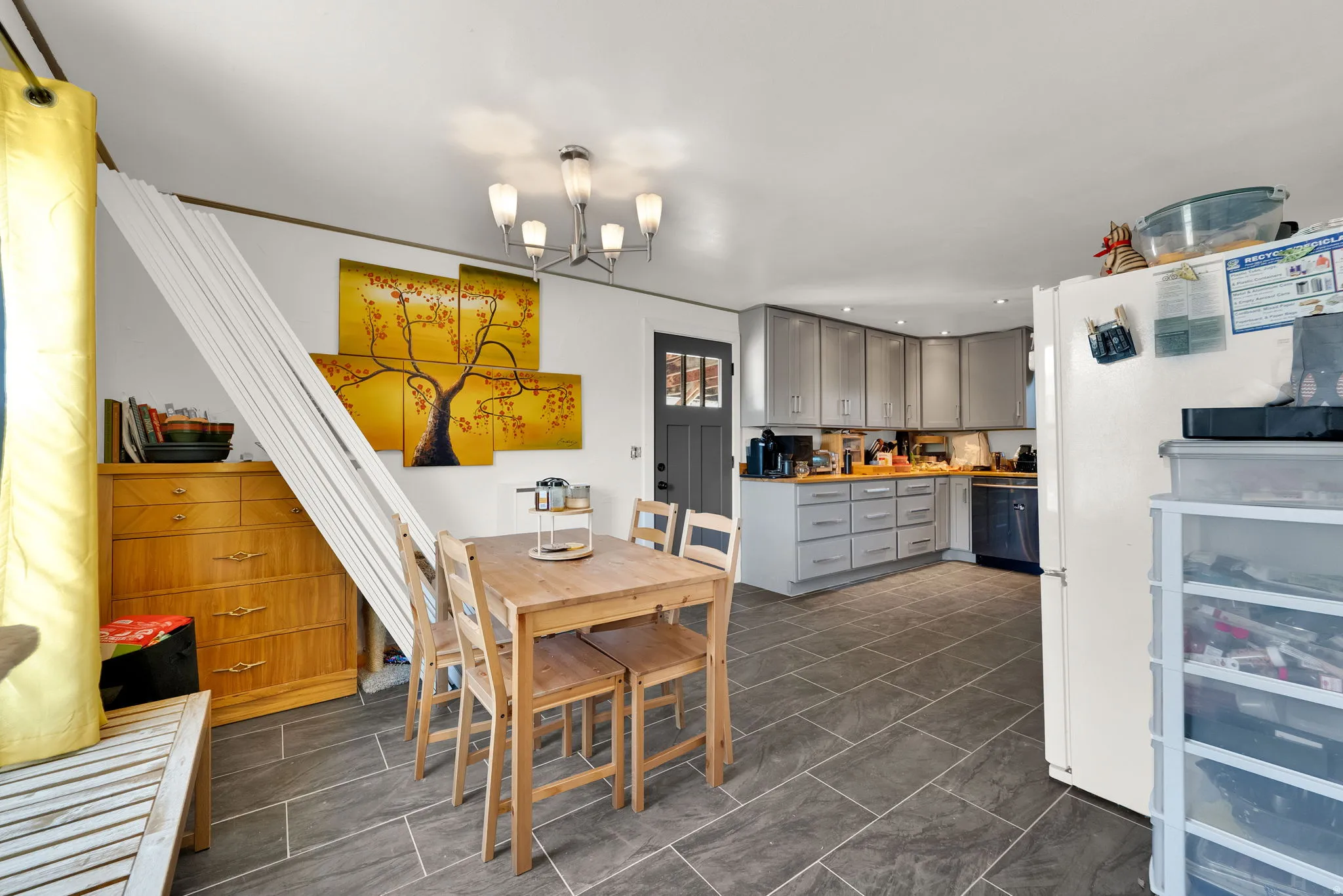 Open-concept kitchen and dining area featuring slate-style tile flooring, light gray cabinetry, wood-finish countertops, and recessed lighting