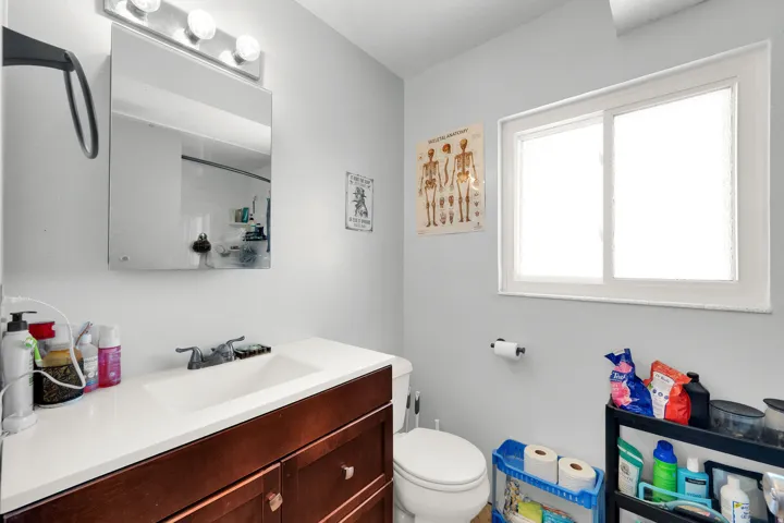 Bathroom featuring a wood-finish vanity with an integrated sink, a medicine cabinet, and a window with privacy glass
