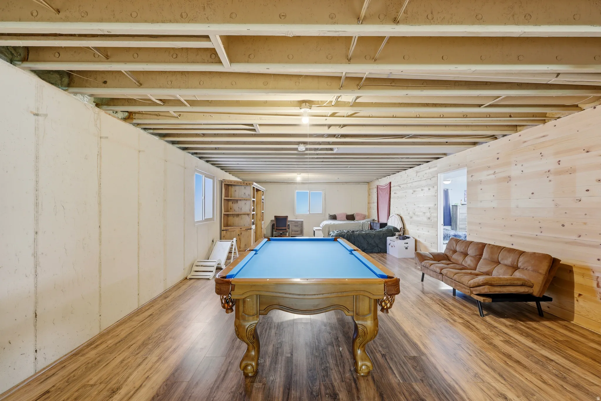 Expansive basement family room featuring wood-finish flooring and an exposed beam ceiling