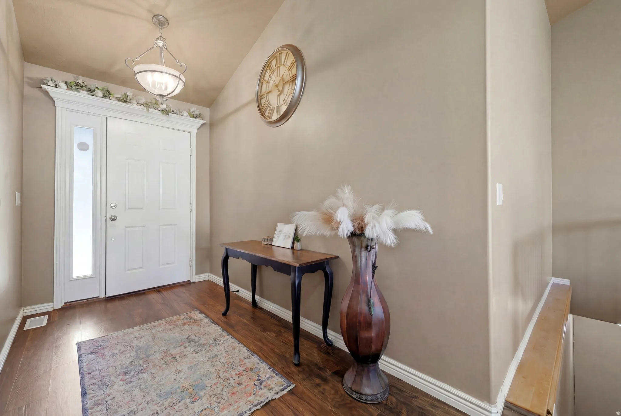 Entryway featuring wood-finish flooring, a white paneled door with an adjacent sidelight, and a decorative overhead light fixture