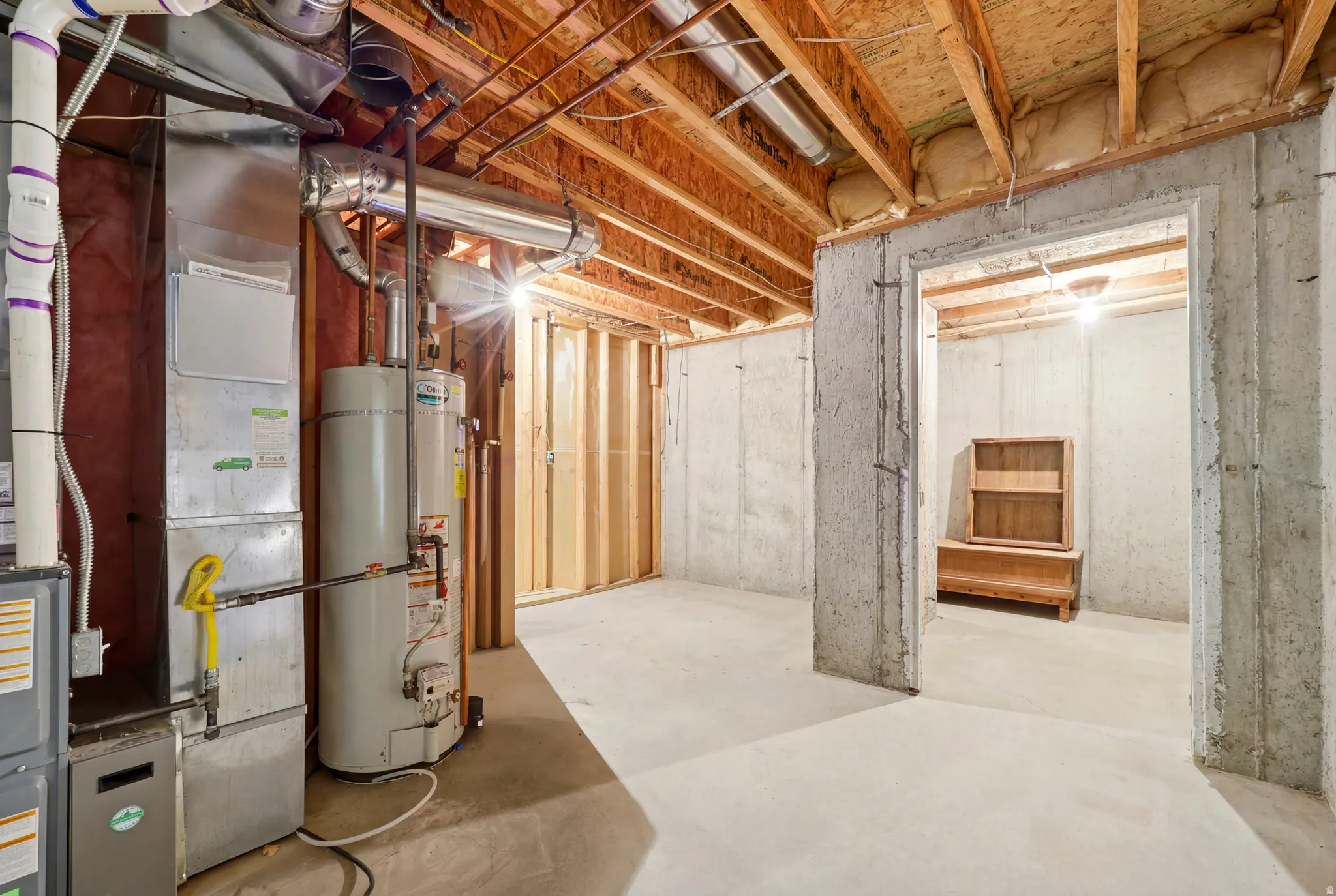 Unfinished basement with concrete flooring and exposed wooden ceiling joists