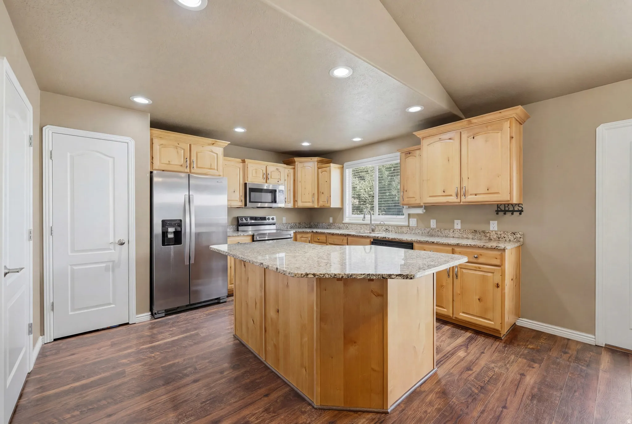 Kitchen featuring a central island with a granite countertop, wood-finish flooring, and recessed lighting