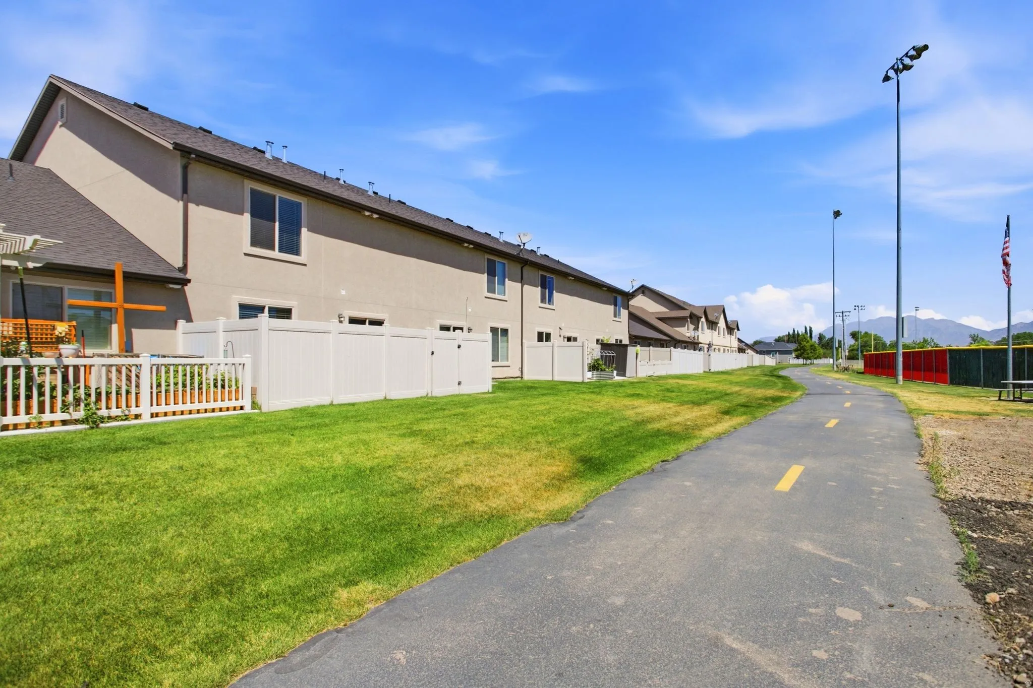 Multi-level townhome featuring a neutral stucco exterior and dark-shingle roofing