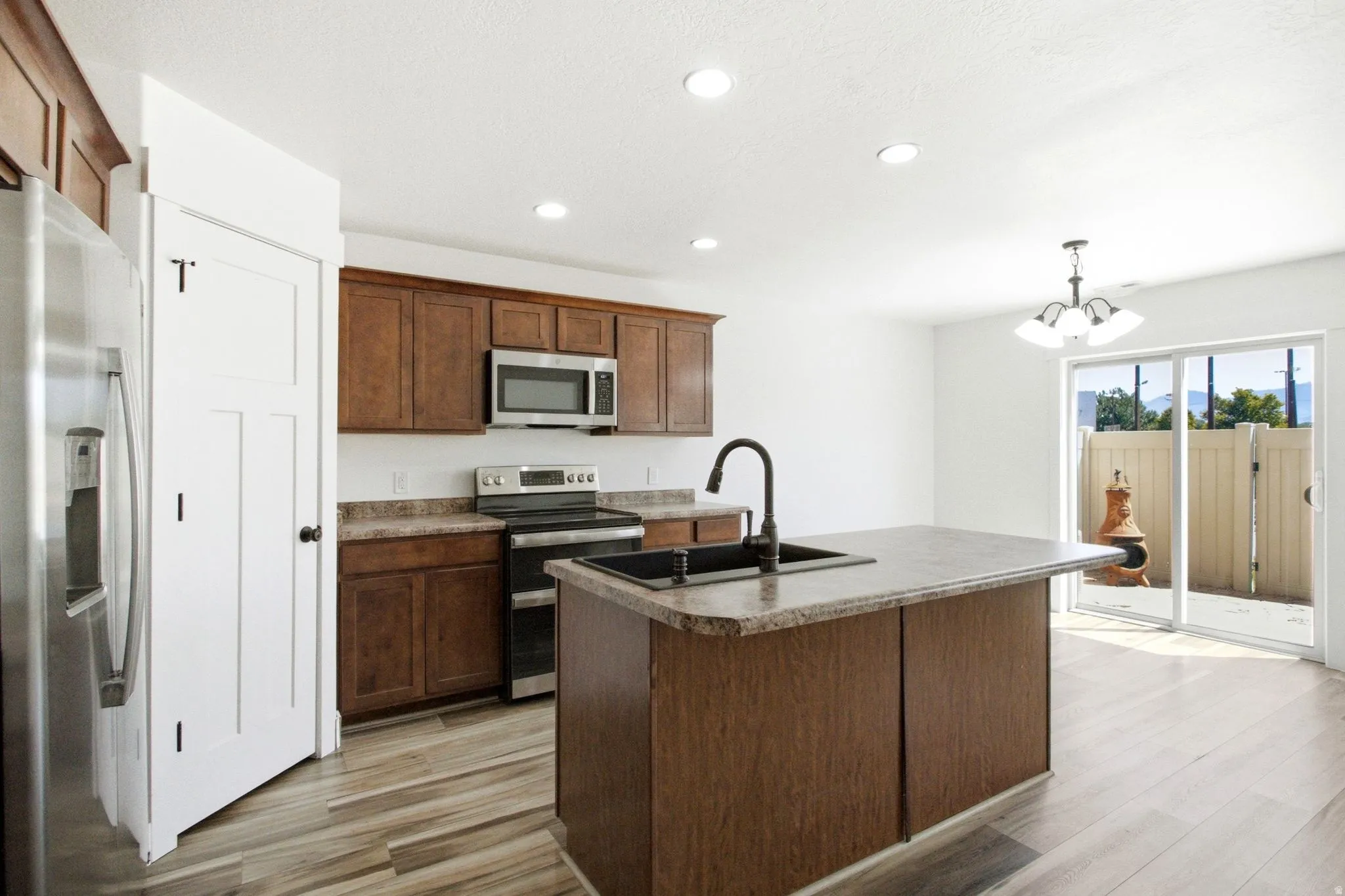 Kitchen featuring wood-finish flooring, recessed lighting, and a center island with sink
