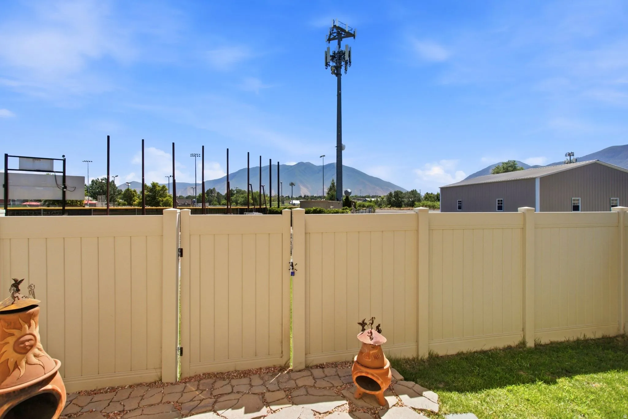 Expansive outdoor space featuring a beige privacy fence and a stone patio
