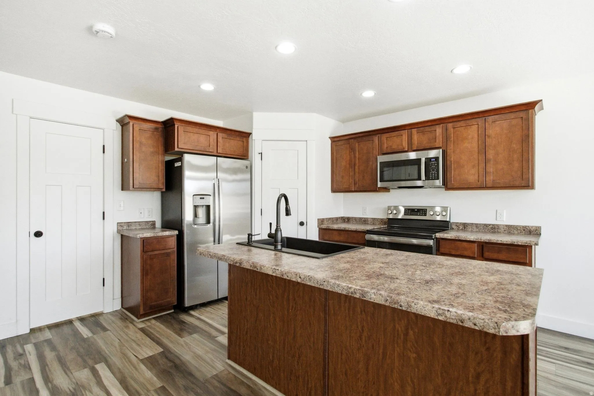 Kitchen with wood-finish flooring, recessed lighting, and white walls