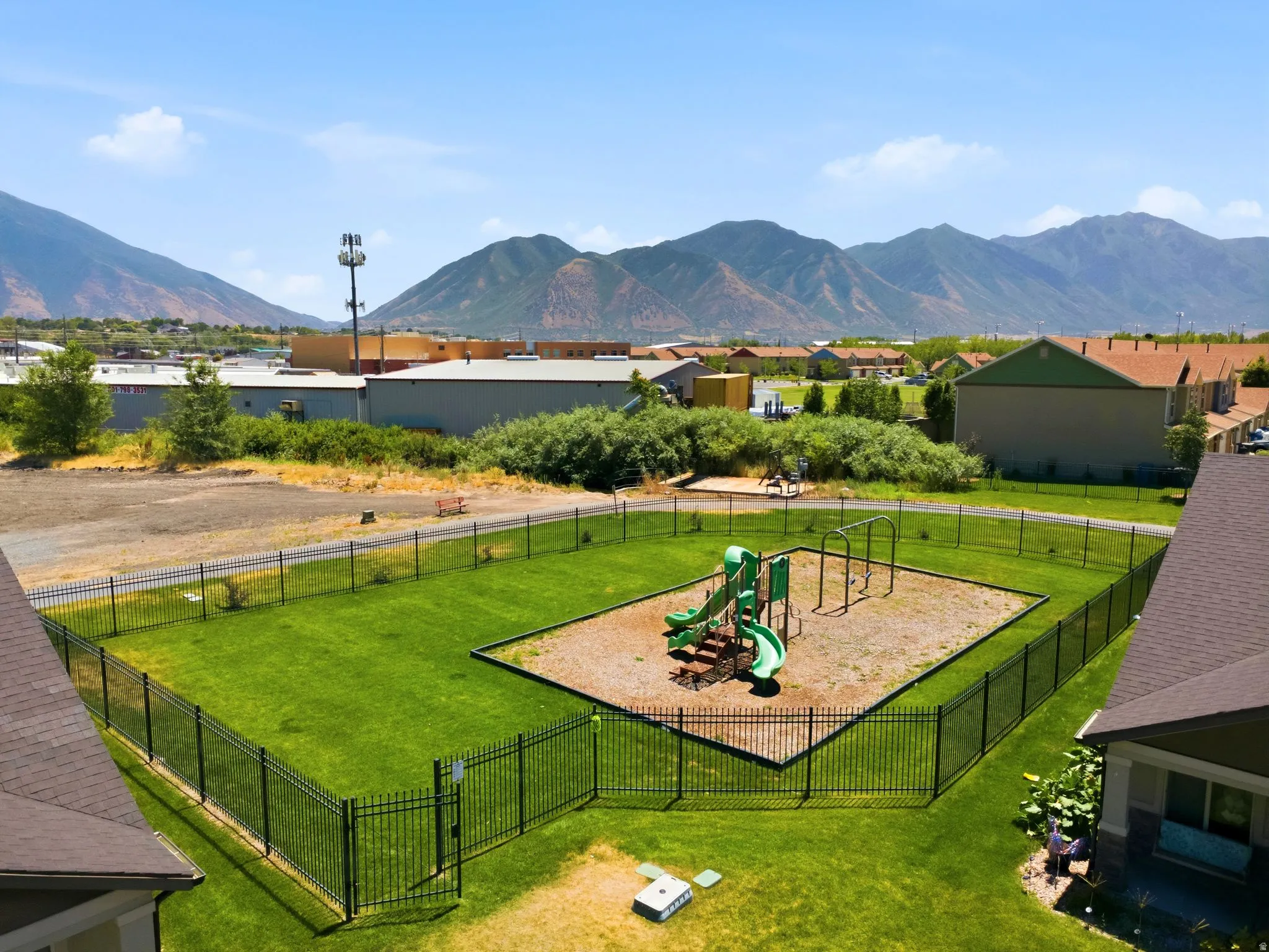 Fenced green space featuring a playground with slides and swings