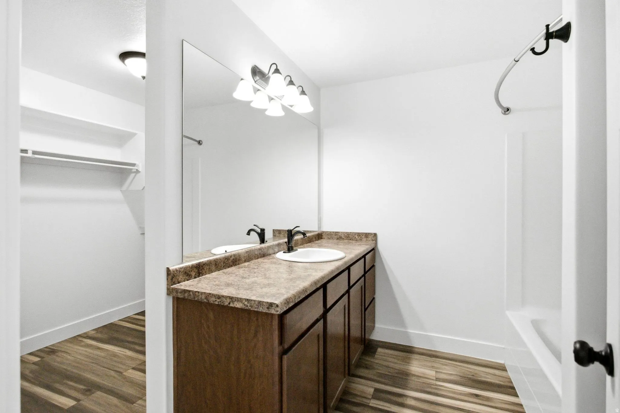 Bathroom featuring a double vanity with wood-finish cabinetry, a large mirror, and a five-light fixture