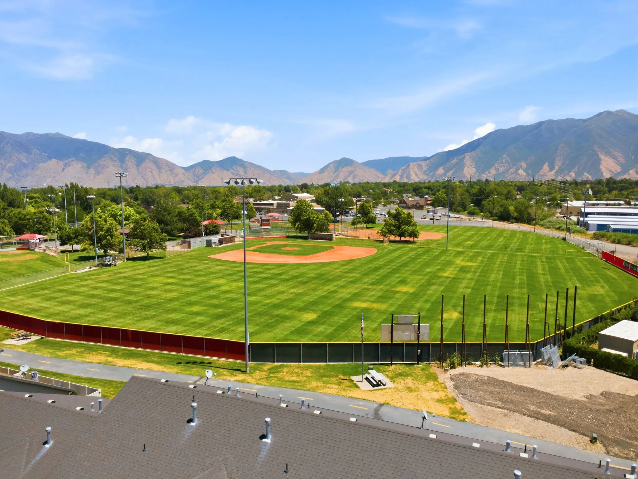 Baseball field featuring a manicured outfield, dirt infield, perimeter fencing, and distant mountain scenery