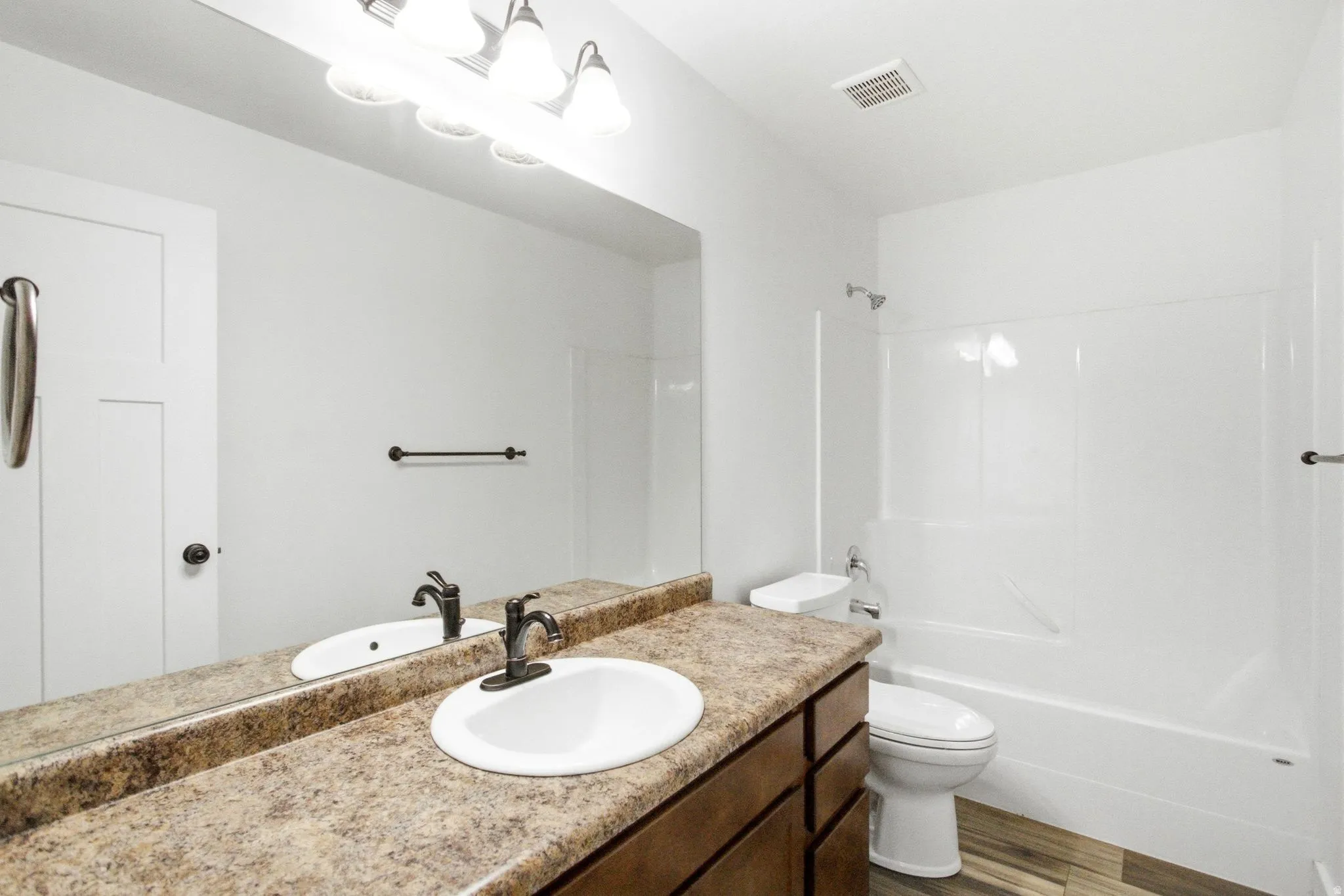 Bathroom featuring a dual-sink vanity with a speckled countertop, dark wood-finish cabinetry, and oil-rubbed bronze fixtures