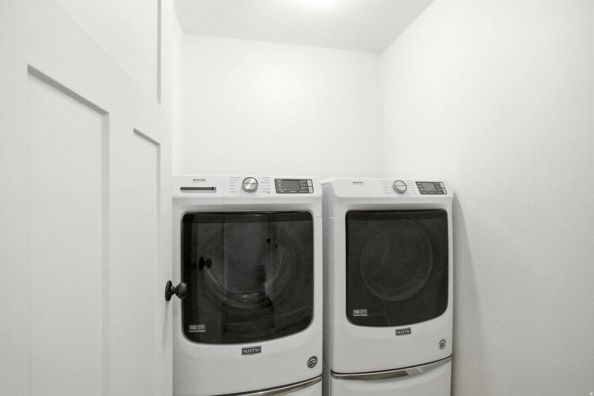 Dedicated utility space featuring a washer and dryer, recessed overhead lighting, and a white paneled door