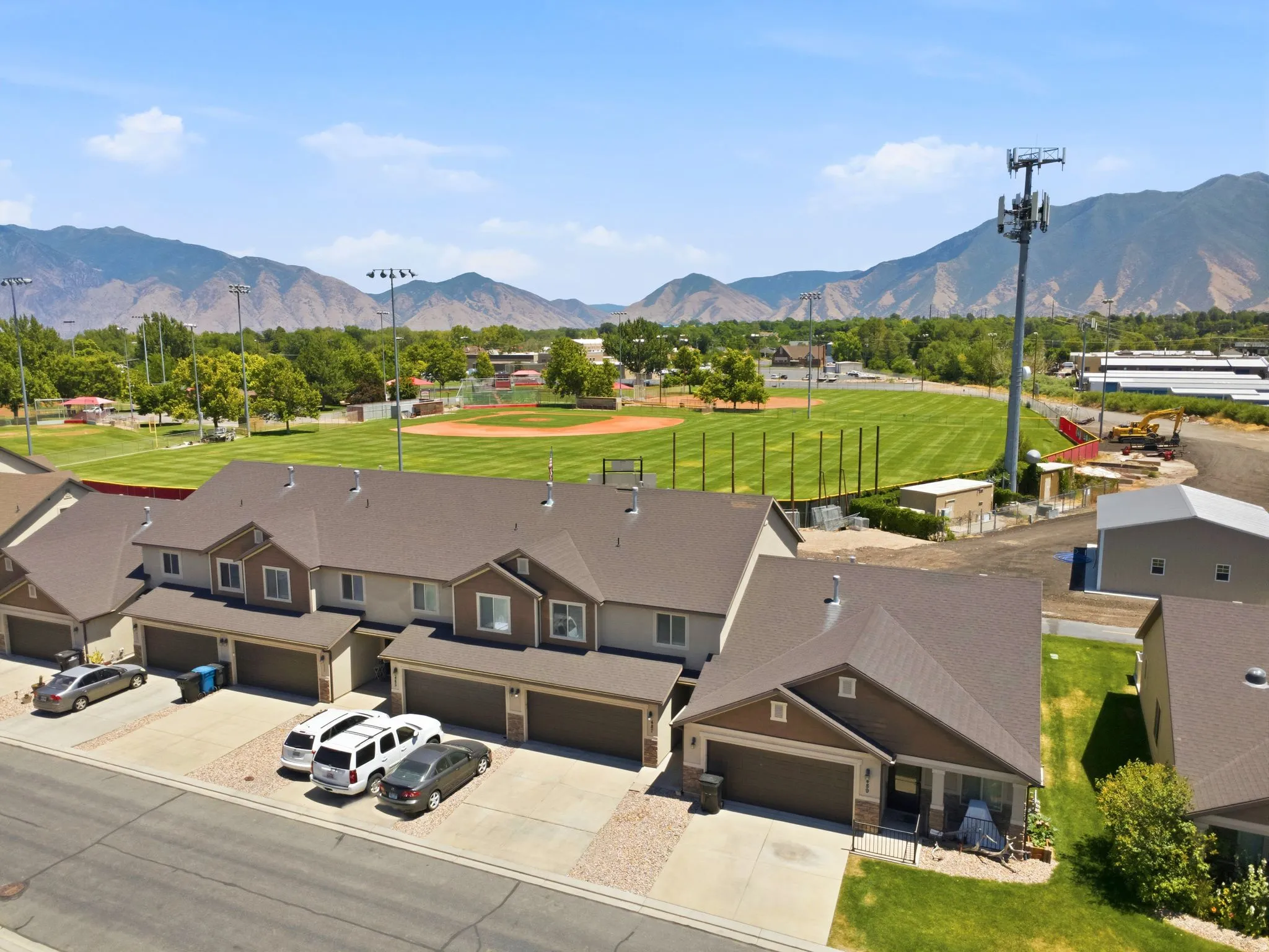 Townhome development featuring brown and beige siding, attached garages, and a paved driveway