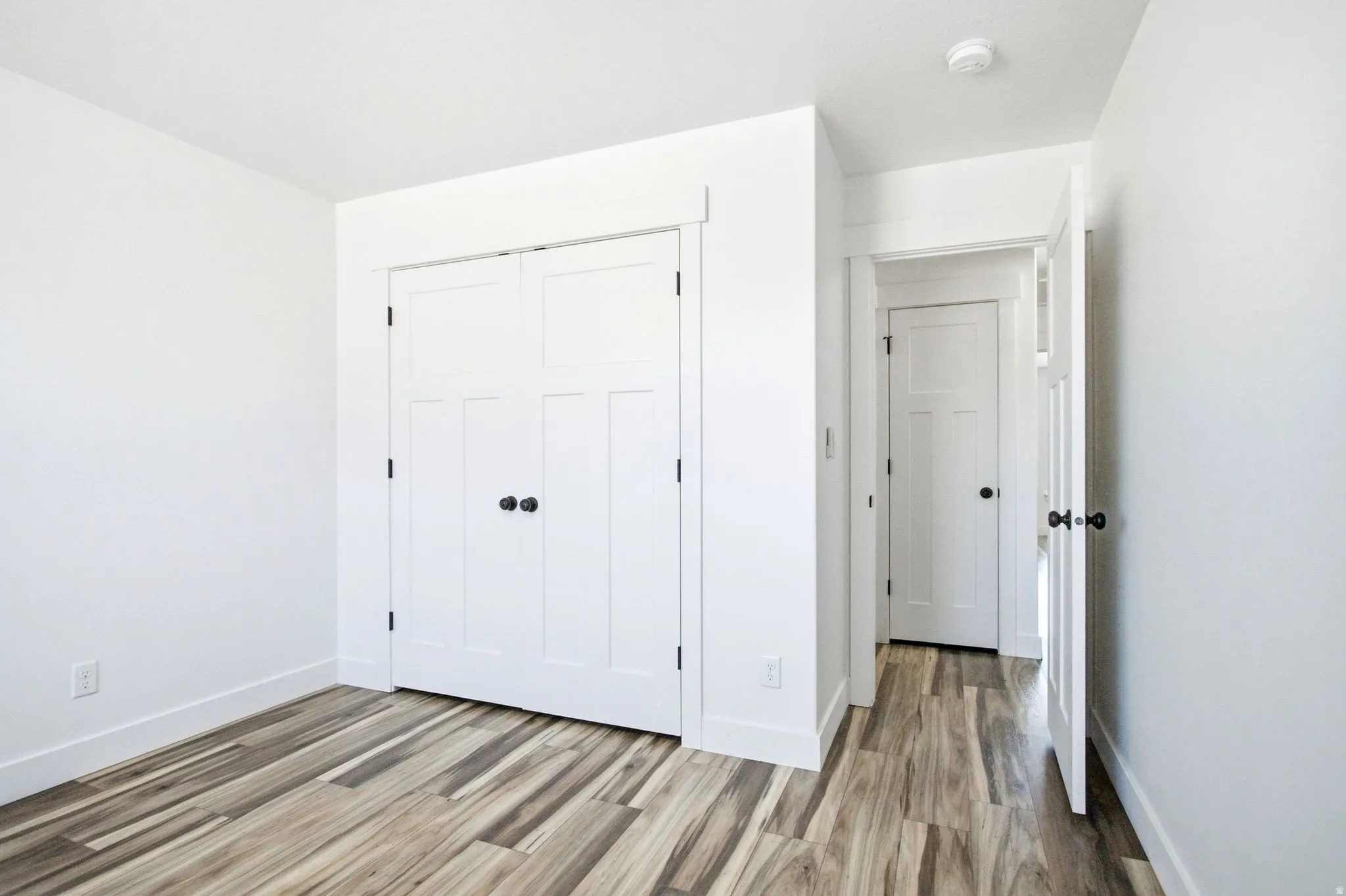 Room featuring wood-finish flooring, white walls, and bright white trim