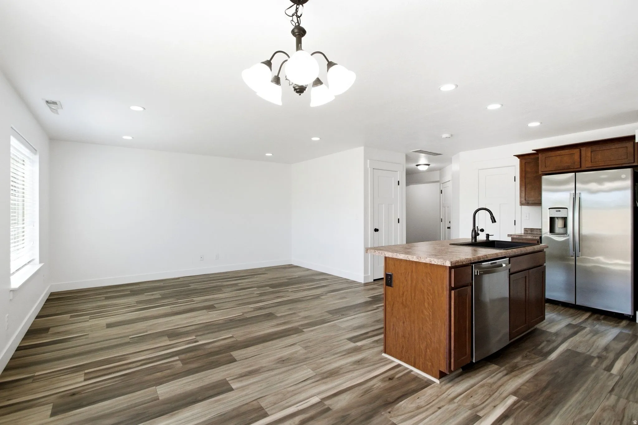 Open-concept living space featuring wood-finish flooring, recessed lighting, and a window with blinds
