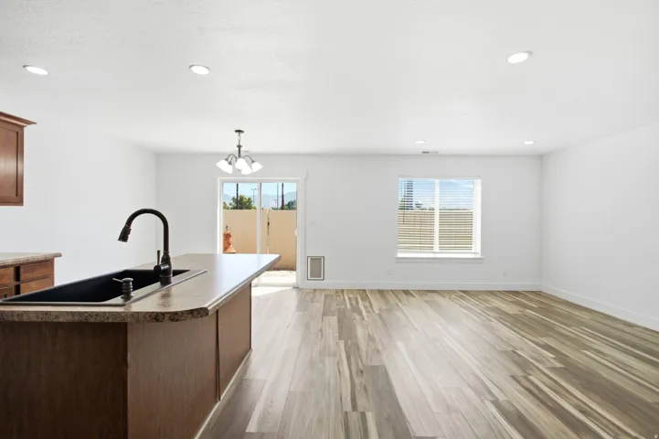 Open concept living space featuring wood-finish flooring, recessed lighting, and a kitchen island with an integrated black sink and matte black faucet