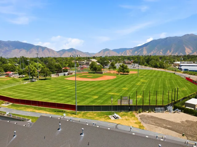 Baseball field featuring a manicured outfield, dirt infield, perimeter fencing, and distant mountain scenery