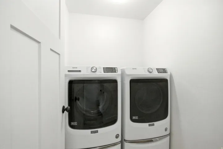 Dedicated utility space featuring a washer and dryer, recessed overhead lighting, and a white paneled door