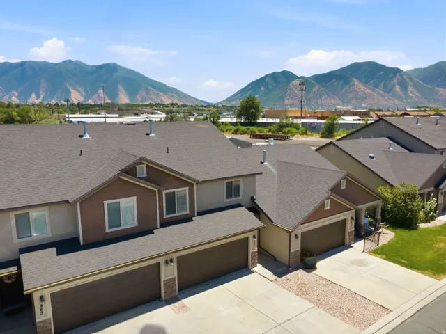 Pitched roofs with asphalt shingles, attached garages featuring panel doors, and concrete driveways