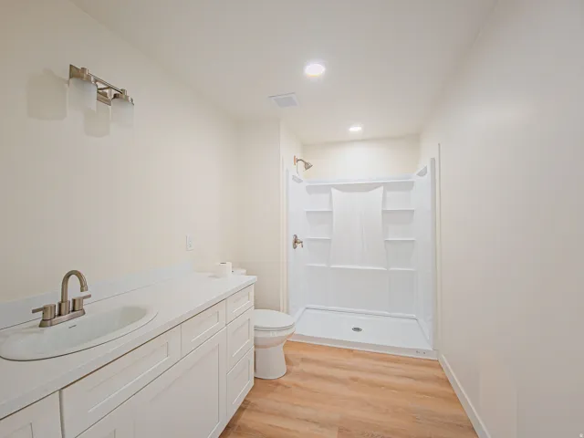 Spacious bathroom featuring a white vanity with an undermount sink, brushed nickel faucet, and white countertop