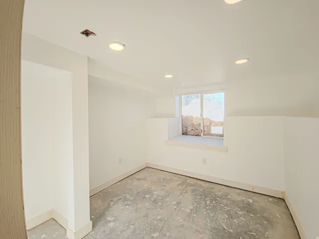 Recessed ceiling lighting, white painted walls, and a sliding window. New carpet on the way!