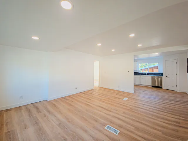 Recessed lighting, wood-finish flooring, white walls, white cabinetry, and stainless steel appliances