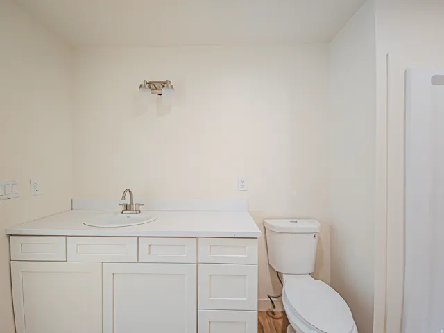 White vanity with a solid surface countertop, undermount sink, and brushed nickel faucet