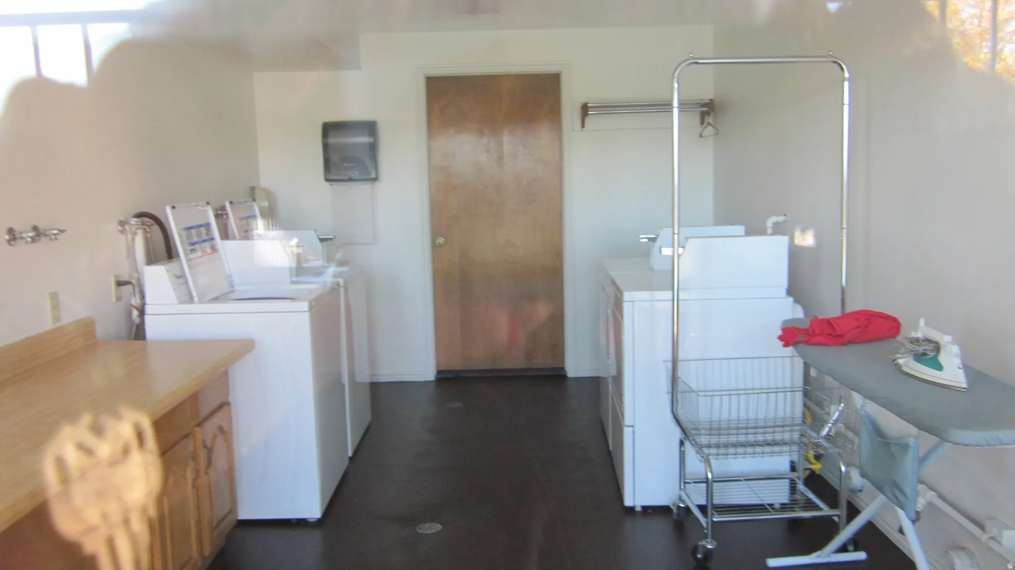 Dedicated laundry facility featuring multiple washing machines, dryers, a built-in counter, and cabinet storage