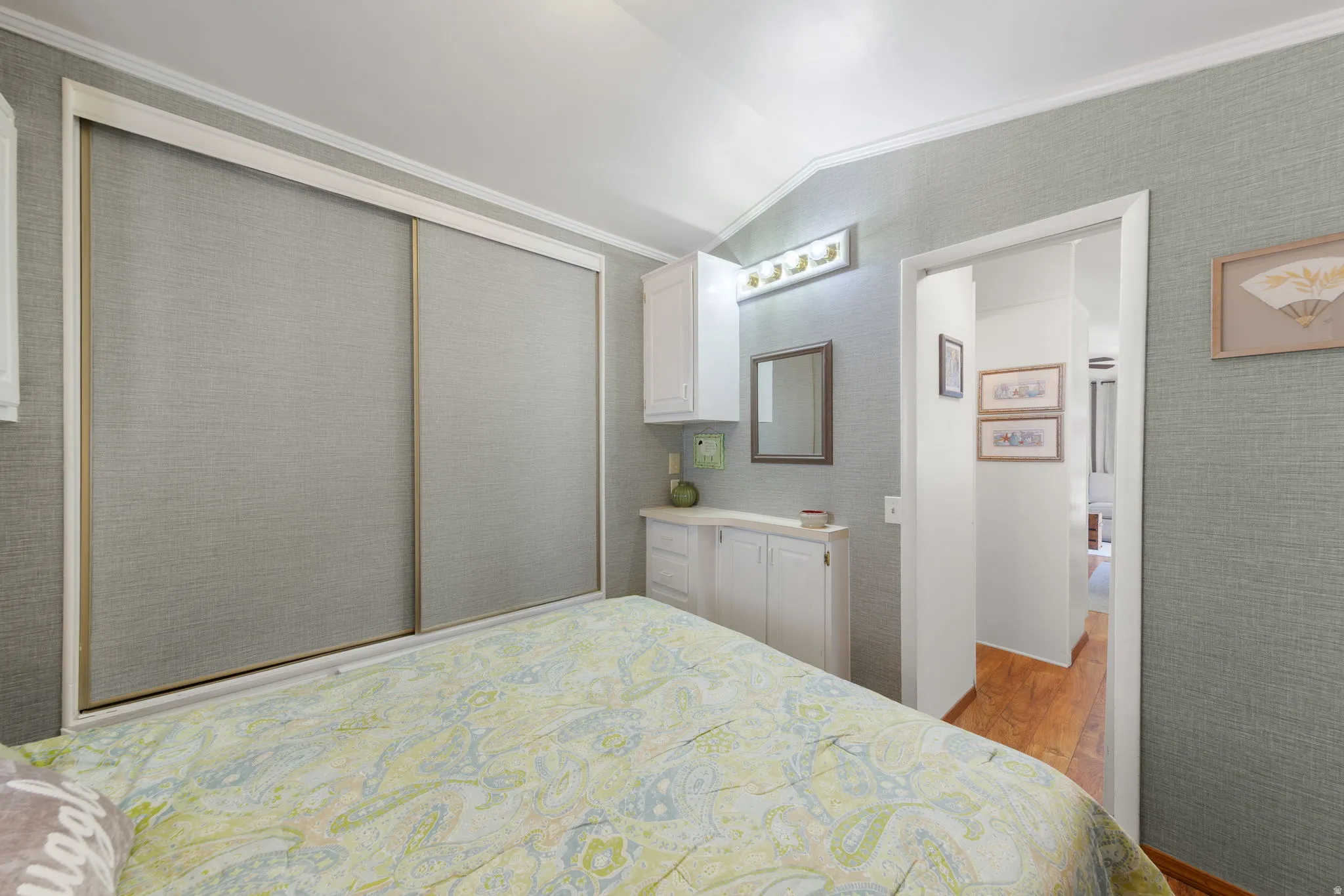 Bedroom featuring light gray textured wall coverings, white crown molding, and sliding closet doors