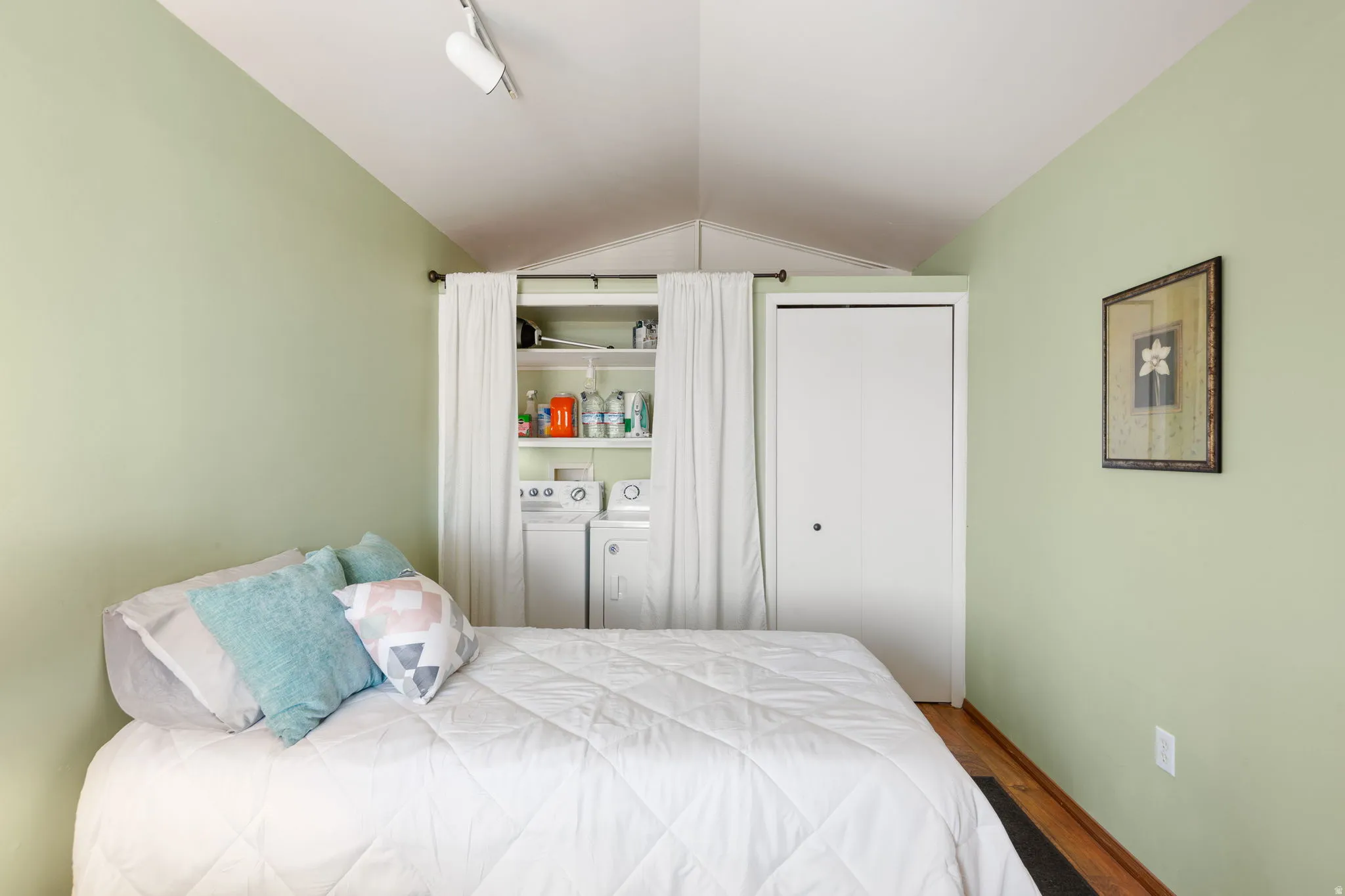 Room with vaulted ceiling, featuring track lighting and light green walls