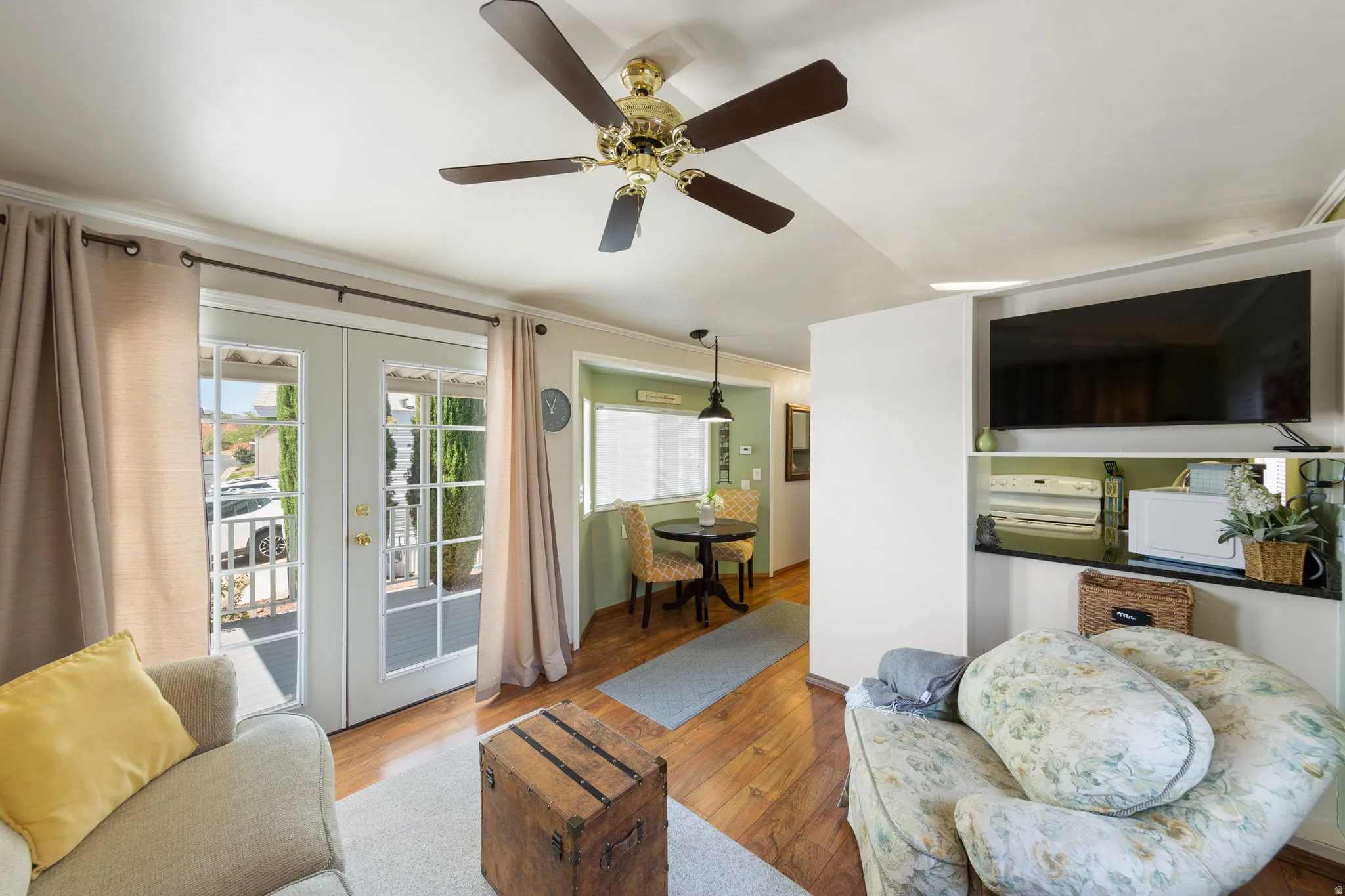 Living space featuring light wood-finish flooring, a ceiling fan, and white walls