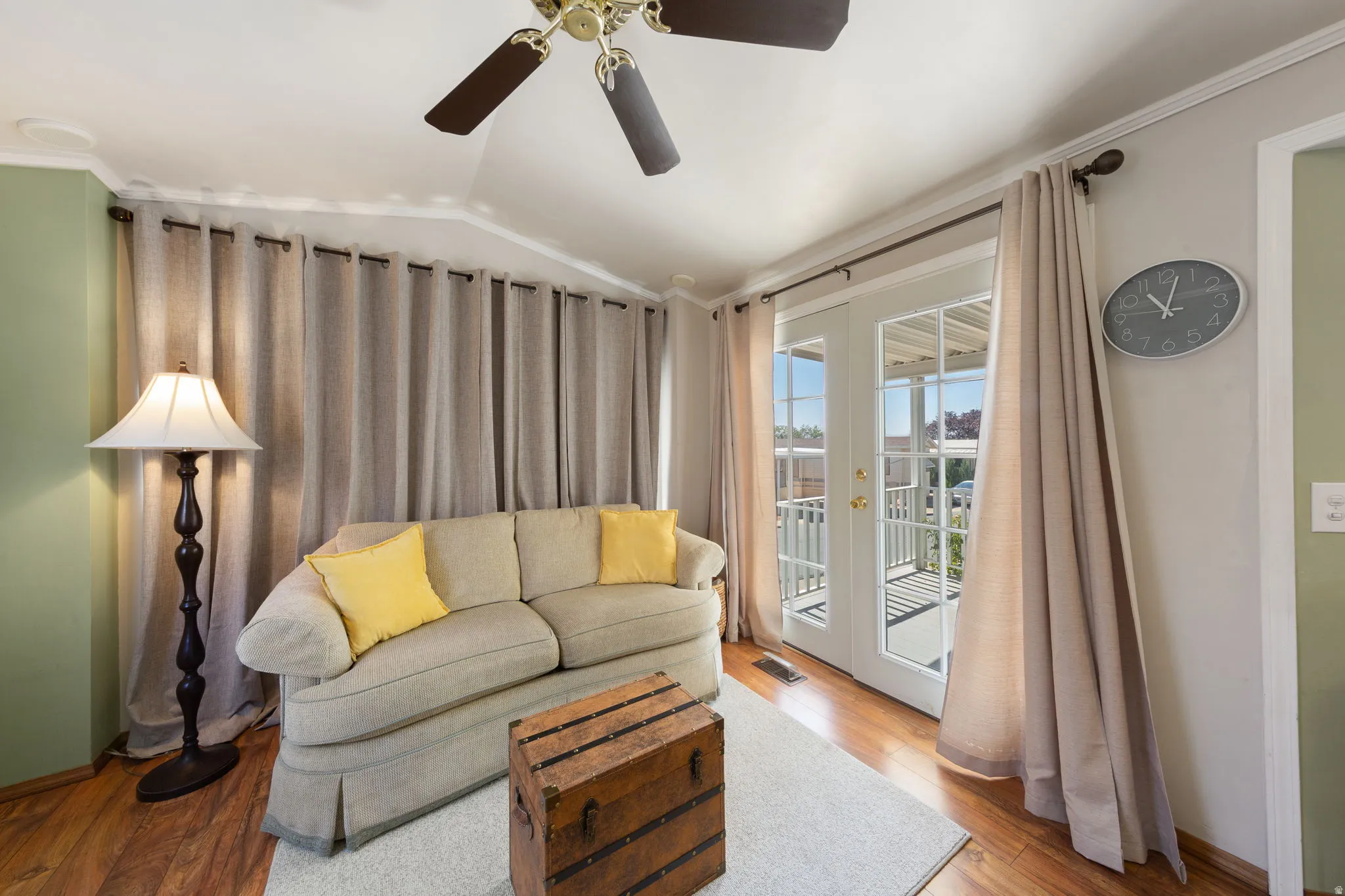 Living area featuring wood-finish flooring, a ceiling fan, and white French doors opening to an exterior balcony