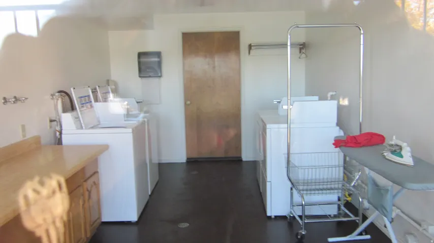 Dedicated laundry facility featuring multiple washing machines, dryers, a built-in counter, and cabinet storage