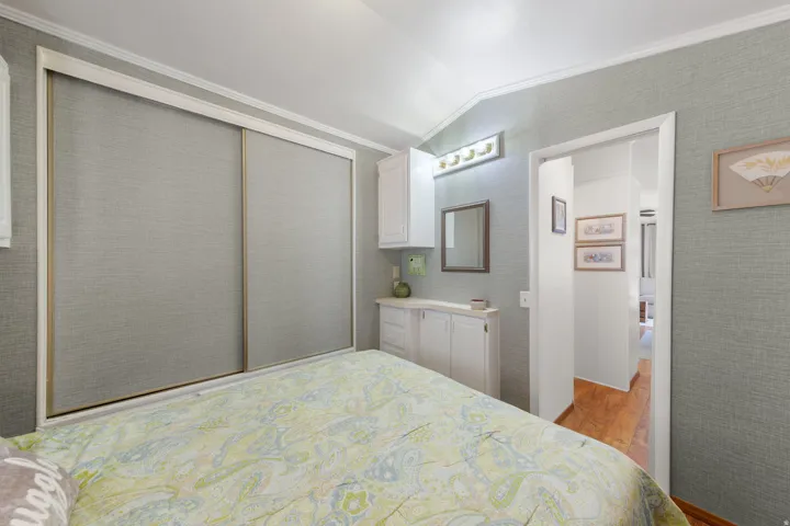 Bedroom featuring light gray textured wall coverings, white crown molding, and sliding closet doors