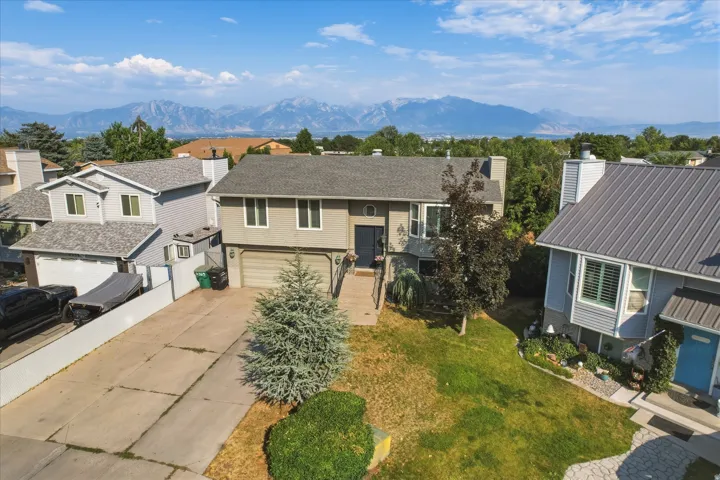 Split-level residence featuring a two-car garage, mature landscaping, and a concrete driveway