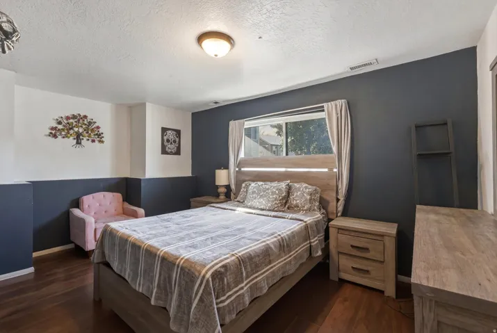 Bedroom featuring wood-finish flooring and a two-tone wall treatment