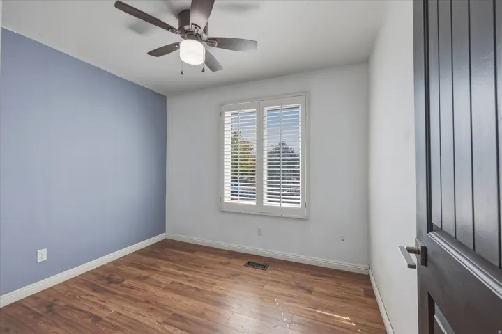 Room featuring wood-finish flooring and a ceiling fan with integrated lighting