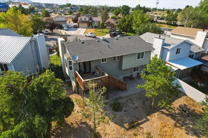 Rear exterior of the property featuring a multi-level wooden deck with stairs, a concrete patio area, and a bay window
