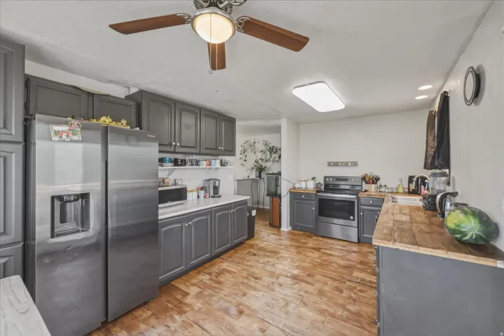 Kitchen featuring wood-finish flooring, stainless steel appliances, dark gray cabinetry, white countertops, and recessed lighting