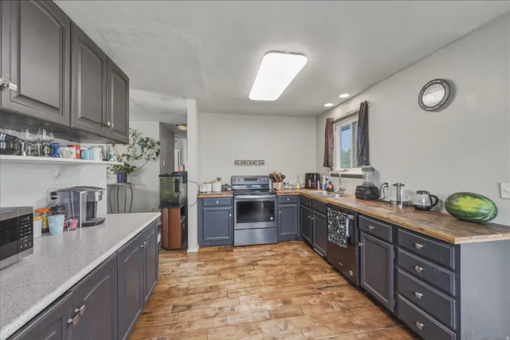 Kitchen featuring dark cabinetry, wood-finish flooring, and a window
